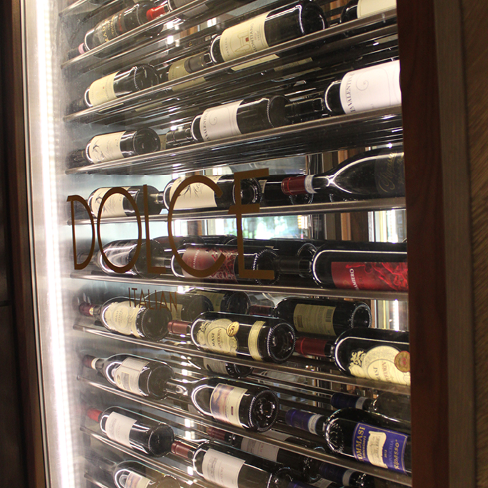 Wine bottles stored in glass case with the words "Dolce Italian"