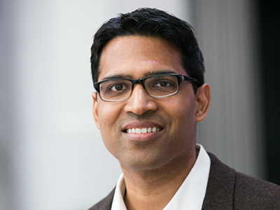 Headshot of tan-skinned man smiling at camera