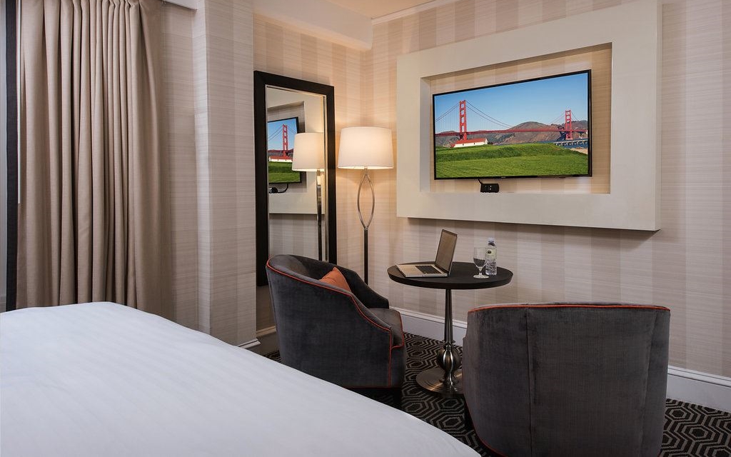 Bedroom with velvet armchairs, a table, and a television