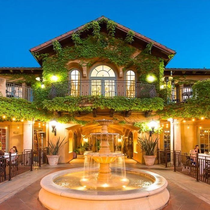 Warmly lit outdoor eating space with fountain and vine-covered walls