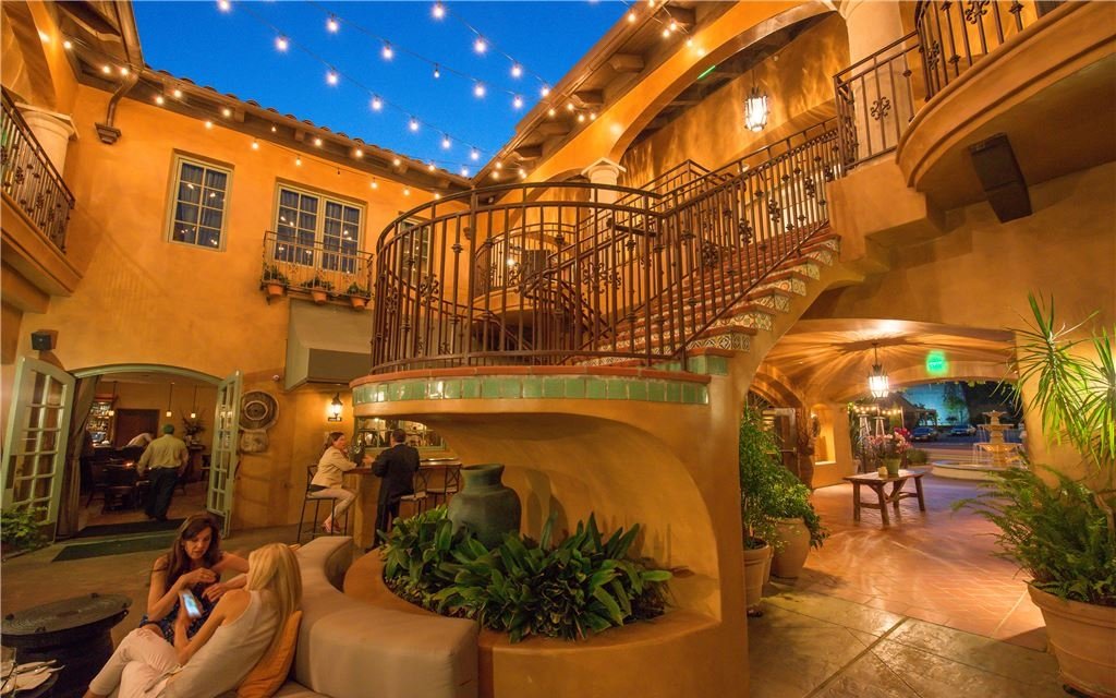 Open-air lobby with terracotta walls, winding staircase, and seating for guests