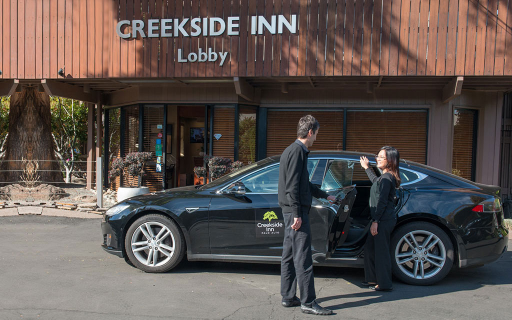 Man holds a car door open for a woman outside the Creekside Inn