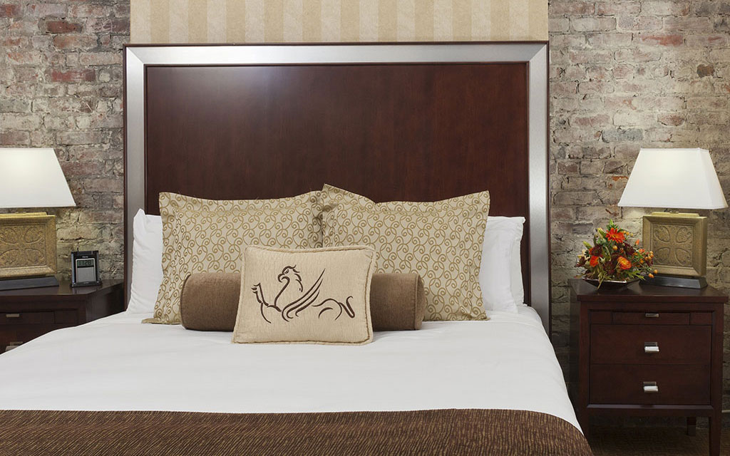 Bed topped with pillows bearing the Griffon Hotel logo