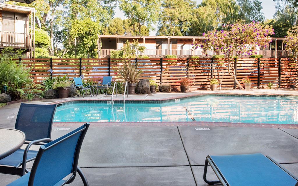 Outdoor pool surrounded by gardens and lawn chairs