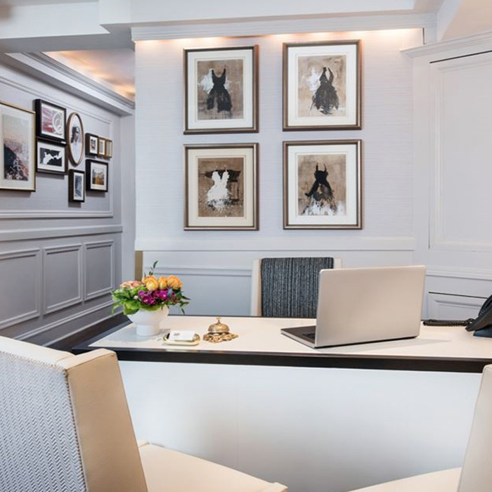 Chairs arranged around a desk in a room with walls covered in paintings