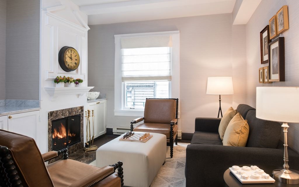 Armchairs and couches in a room with a hearth and coffee table with chess board