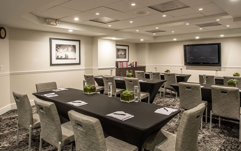 Conference table and chairs set for a meeting with a television on the far wall