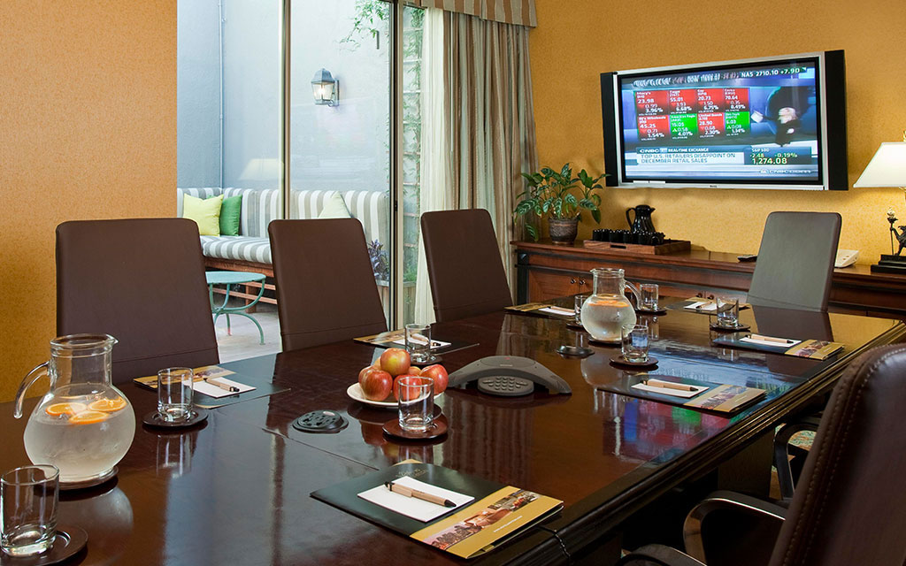 Conference table and chairs set for a meeting with a television on the far wall