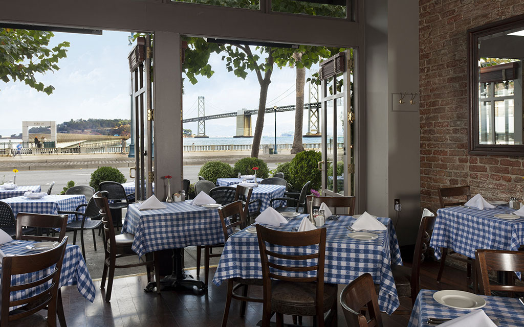 Indoor/outdoor dining space overlooking water and bridge